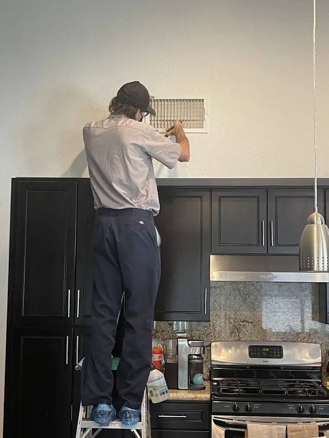 Technician inspecting an air vent during HVAC service in Palm Coast